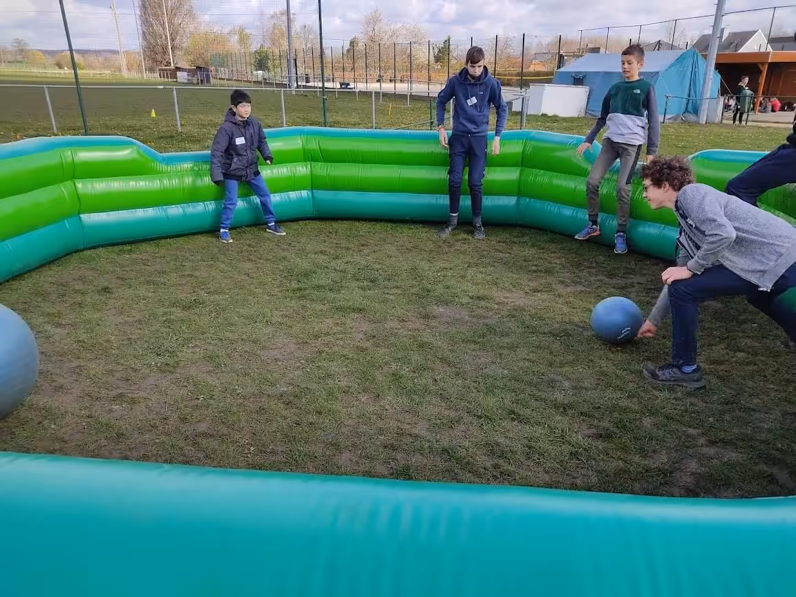 Kinderen spelen in een opblaasbare arena met bal.