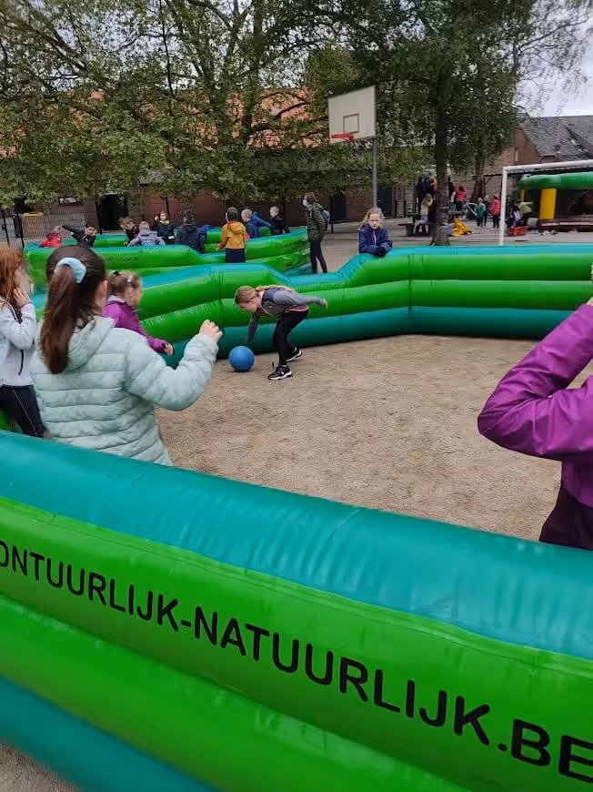 Kinderen spelen in groen opblaasbaar sportveld