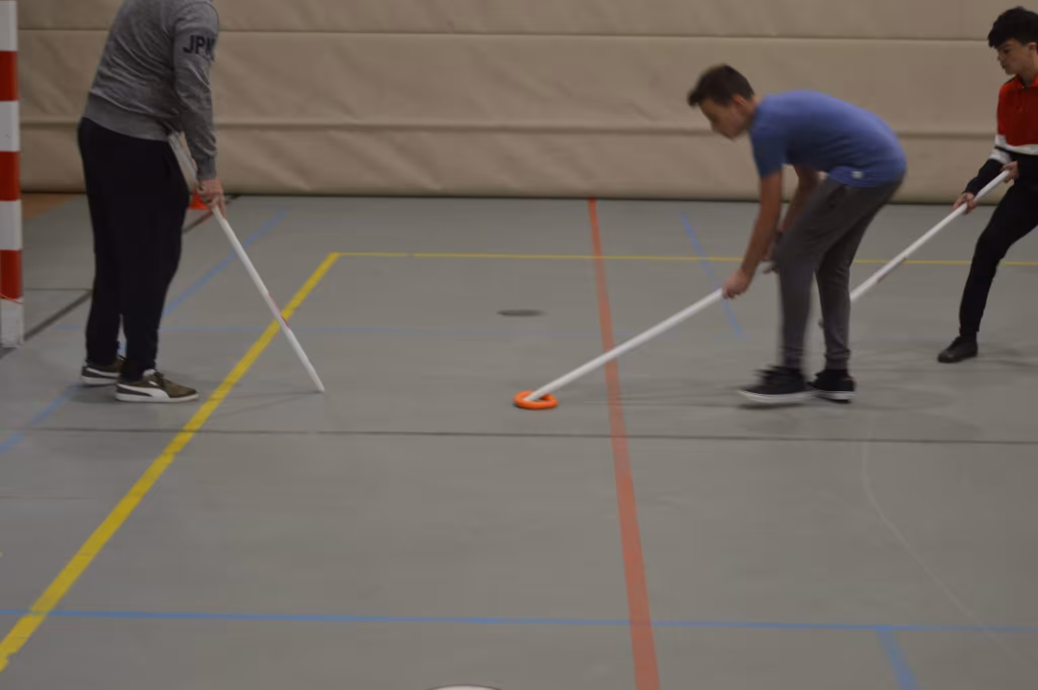 Mensen spelen aangepast hockey in een sportzaal.
