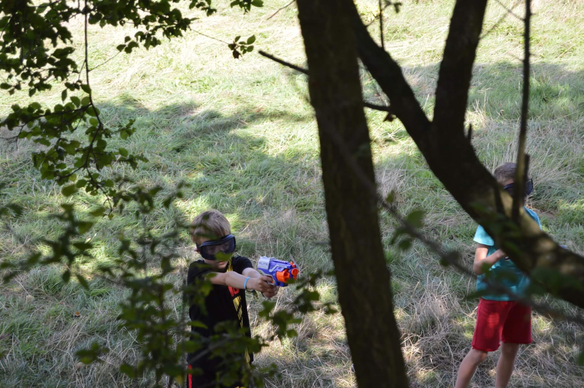 Nerf jongen achter boom