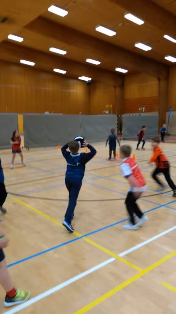 Kinderen spelen basketbal in sporthal