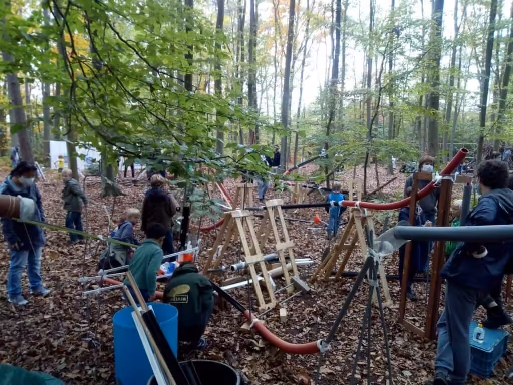 Kinderen spelen in bos met zelfgemaakte structuren.