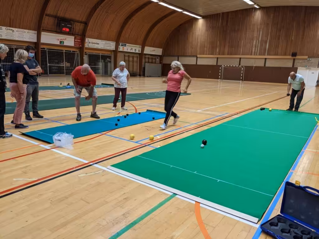 Senioren spelen indoor boccia in een sporthal.