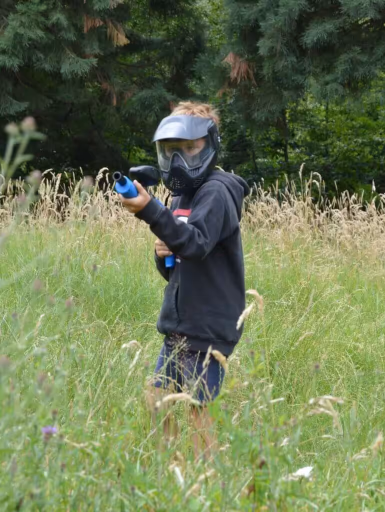 Kind speelt paintball in het grasveld.