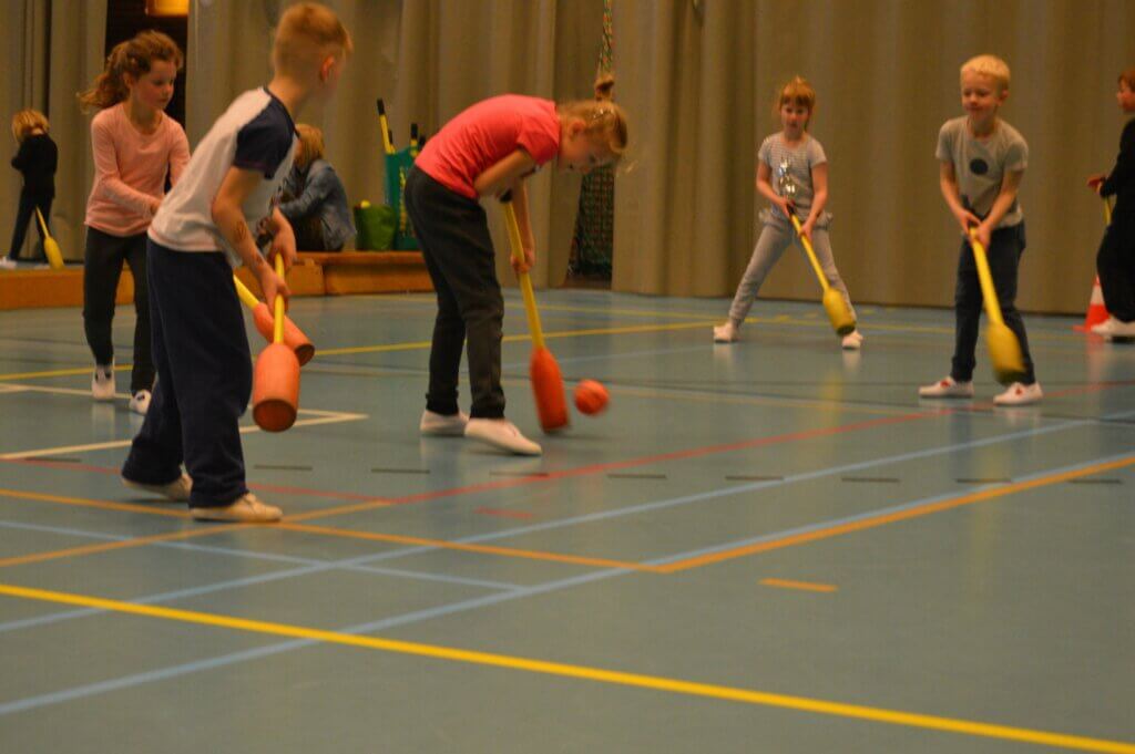 kinderen spelen knotshockey binnen
