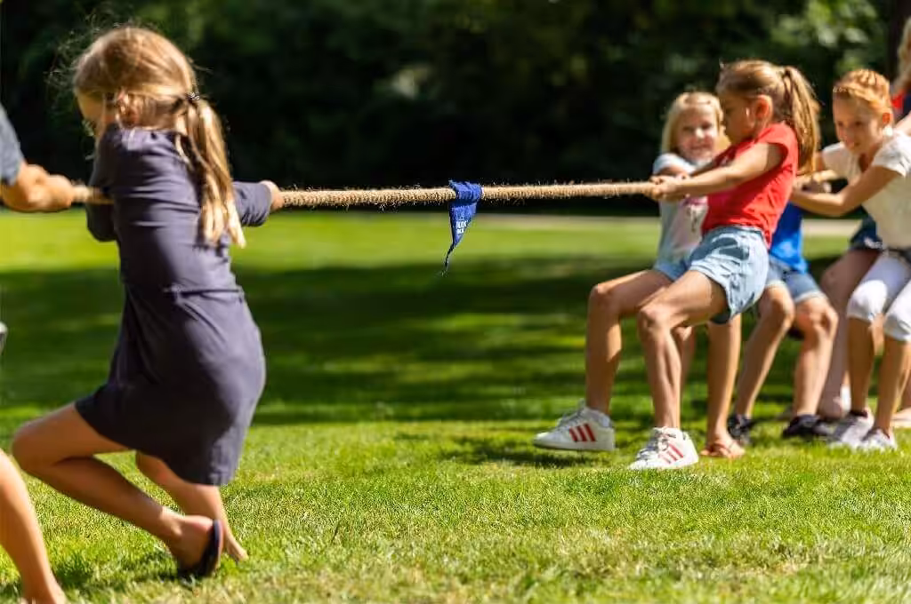 Kinderen spelen touwtrekken op zonnige dag buiten