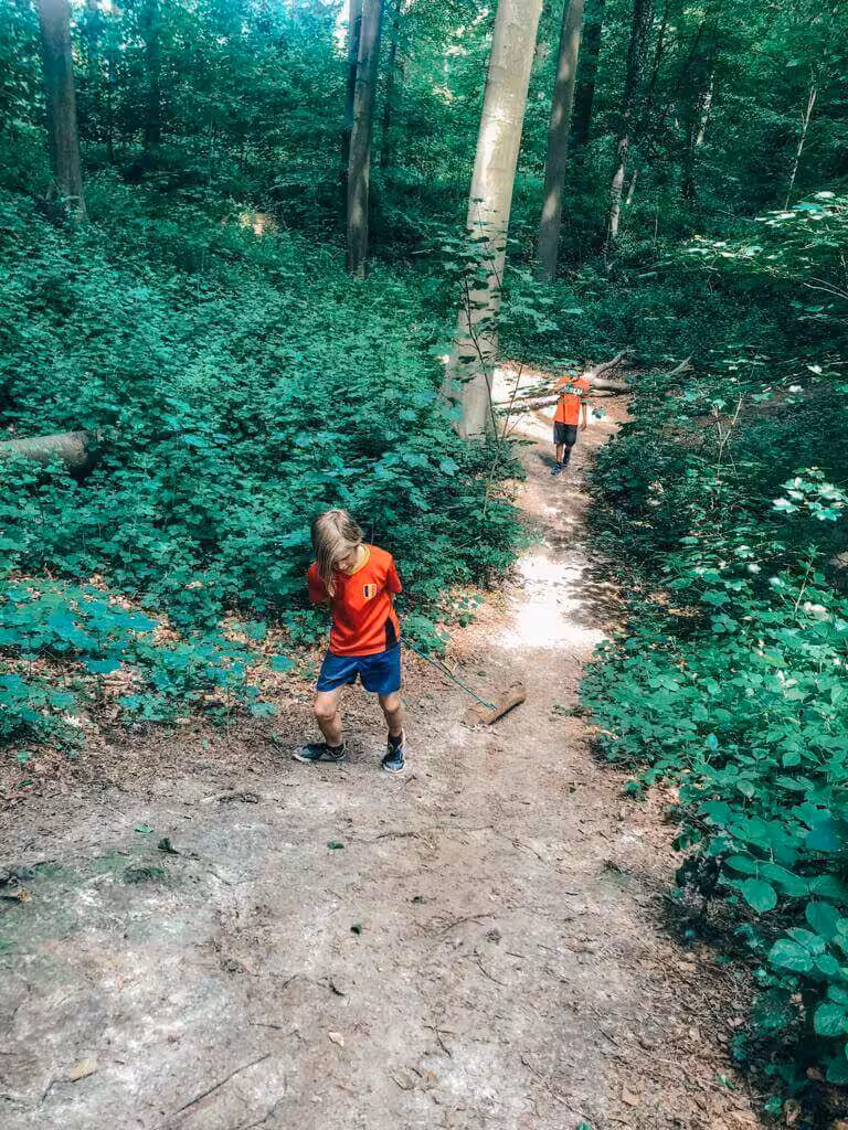 Kinderen wandelen door een bos op modderig pad.