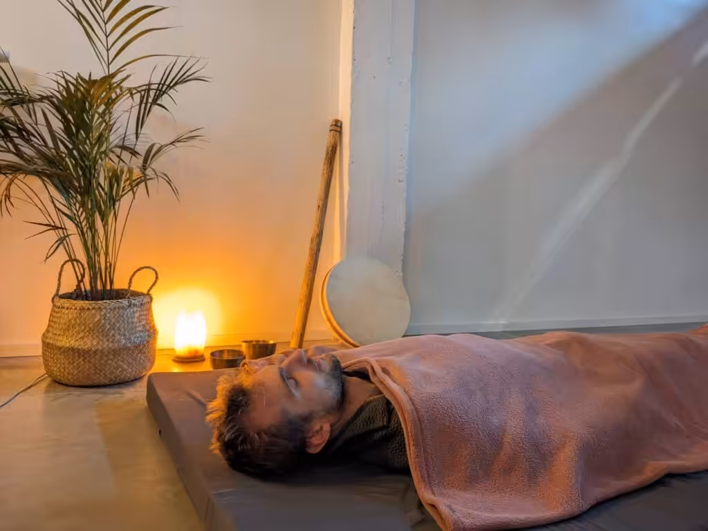 Man slaapt naast plant en lamp in zen sfeer.