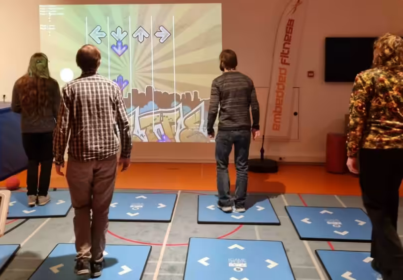 Mensen spelen dansspel op interactieve matten.