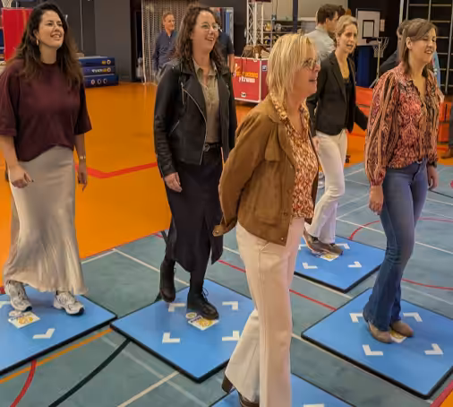 Groep mensen speelt een interactief spel in een zaal.