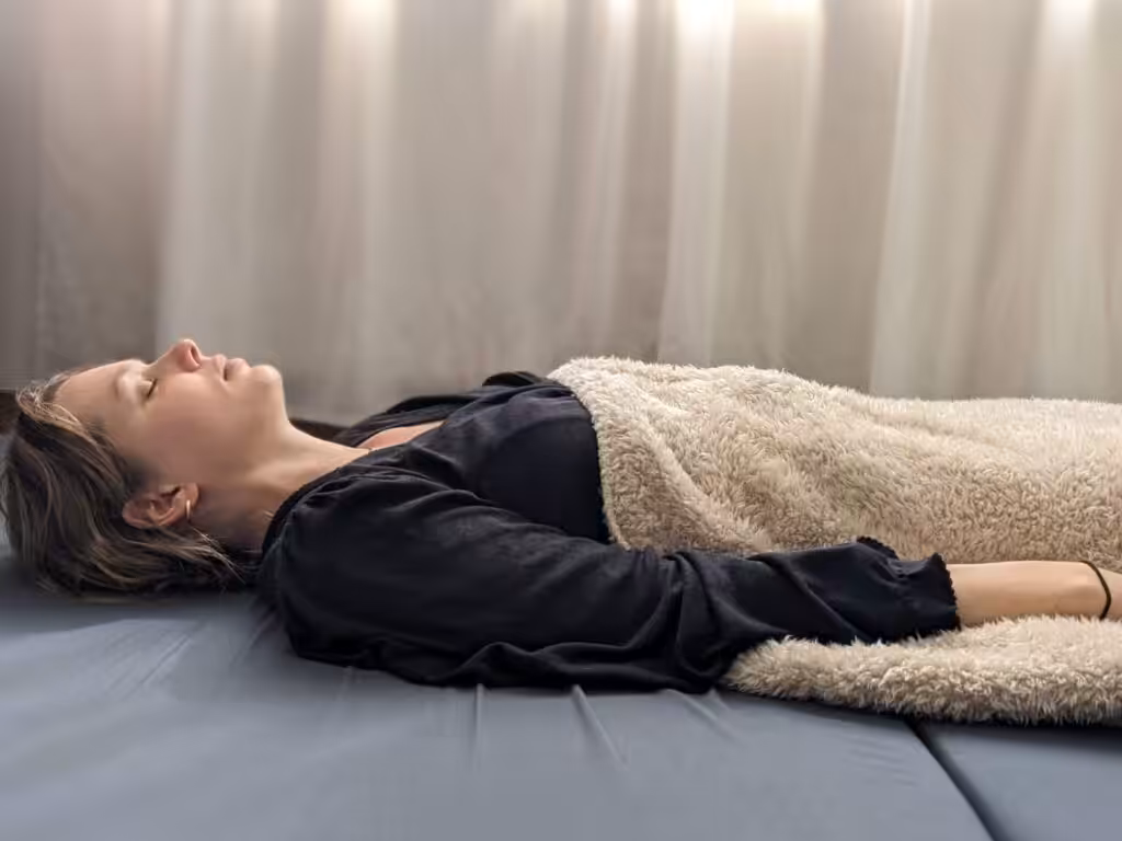 Vrouw ontspant liggend onder deken in zonlicht.